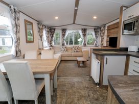 A living room with a sofa and dining area at Woodlands Gold (WO 41) in Ruthin