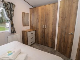 A bedroom with a wardrobe and a chest of drawers at Woodlands Gold (WO 41) in Ruthin
