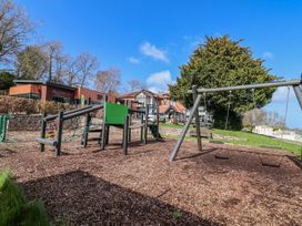 A playground with swings and climbing frame at Woodlands Gold (WO 41) Ruthin