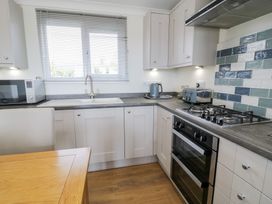 A kitchen with appliances including a microwave, sink, and gas stove at Platinum Lodge (503) Talybont