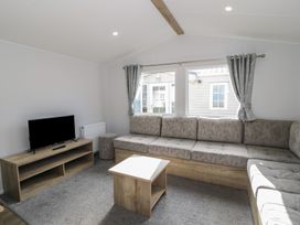 A living room with a sofa, television, and coffee table at Lido Silver Plus 111 Prestatyn