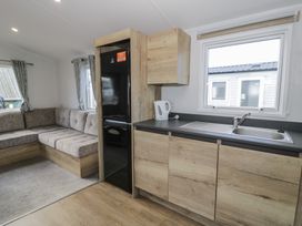 A kitchen with a sofa and refrigerator at Lido Silver Plus 111 Prestatyn