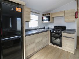 A kitchen with appliances and wooden storage at Lido Silver Plus 111 Prestatyn
