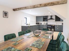 A kitchen and dining area with green chairs around a wooden table set with leaf patterned placemats at Sally's Barn in Weston Rhyn