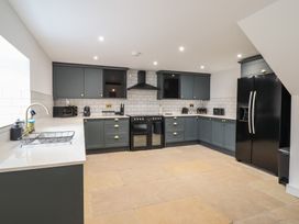 A kitchen with grey cabinets a black refrigerator a black oven a black range hood and white tiled backsplash at Sally's Barn in Weston Rhyn