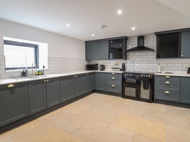 A kitchen with dark green cabinets white countertops subway tile backsplash and a black oven at Sally's Barn in Weston Rhyn