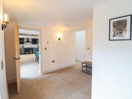 A hallway with stone tile floor a bench and wall lights leading to a kitchen at Sally's Barn in Weston Rhyn