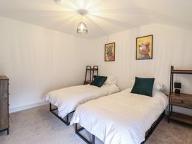 A bedroom with two single beds with white bedding and green cushions at Sally's Barn in Weston Rhyn