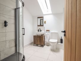 A bathroom with a shower enclosure toilet and sink with cabinet under a skylight at Sally's Barn in Weston Rhyn