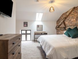 A bedroom with a bed with white bedding and green pillows a wooden dresser a small desk with a mirror and a skylight in the ceiling at Sally's Barn Weston Rhyn