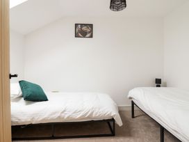A bedroom with two single beds a green pillow a small black lamp and a framed picture on the wall at Sally's Barn in Weston Rhyn