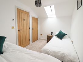 A bedroom with two single beds green pillows wooden doors and a skylight window at Sally's Barn in Weston Rhyn