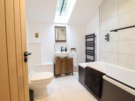 A bathroom with a toilet a sink with a cabinet a bathtub with a towel and a skylight at Sally's Barn in Weston Rhyn