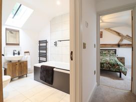 A bathroom with a bathtub sink and towel rack next to a bedroom with a bed and wooden beams at Sally's Barn in Weston Rhyn