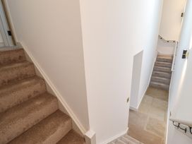 A stairway with beige carpet leading up and stone tile flooring leading down at Sally's Barn in Weston Rhyn