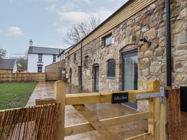 A stone barn exterior with wooden gate and fenced yard at Sally's Barn in Weston Rhyn