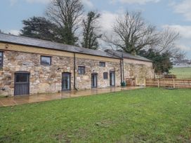 A stone barn building with glass doors and windows and a grassy yard at Sally's Barn in Weston Rhyn