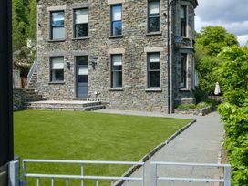 A stone house with a lawn and pathway at Riverside in Ambleside