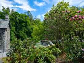 An outdoor area with a building beside trees and flowers at Riverside in Ambleside
