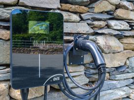 An electric vehicle charger mounted on a stone wall at Riverside in Ambleside