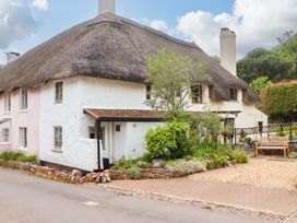 An outdoor view of a thatched roof house with a garden and pathway at 1 Myrtle Cottages Stokeinteignhead