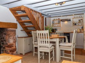 A kitchen with a dining table and staircase at 1 Myrtle Cottages Stokeinteignhead