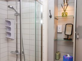 A bathroom with a shower and shelves containing a mirror and decorative items at 1 Myrtle Cottages Stokeinteignhead