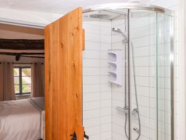 A bathroom with a shower and wooden door at 1 Myrtle Cottages Stokeinteignhead