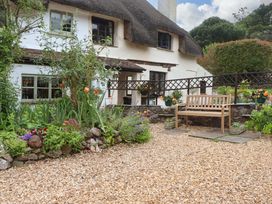 A garden with flowers and a wooden bench at 1 Myrtle Cottages in Stokeinteignhead