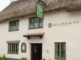 The exterior of a building with a thatched roof and signage at The Church House Inn in Stokeinteignhead