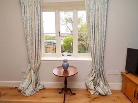 A living room with a table and vase by a window at 9 Longhirst Village in Morpeth