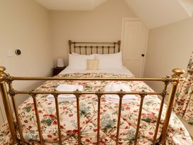 A bedroom with a brass bed and floral bedding at 9 Longhirst Village Morpeth