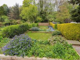 A garden with flowerbeds and a hedge at 9 Longhirst Village, Morpeth