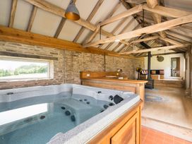 A room with a hot tub, wooden counter, fireplace, and seating at Henhouse Farm in Bodenham