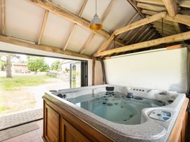 A hot tub in a room with wooden beams at Henhouse Farm in Bodenham