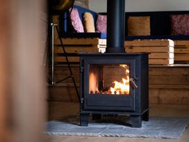 A wood stove with flame in a living room at Henhouse Farm in Bodenham