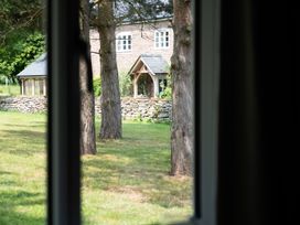 A view of a house and trees from a window at Henhouse Farm Bodenham