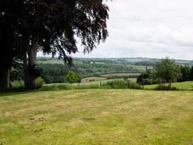 A view of a grassy field with trees and hills at Henhouse Farm in Bodenham