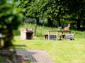 A garden with a barbecue grill and a table set with flowers at Henhouse Farm in Bodenham
