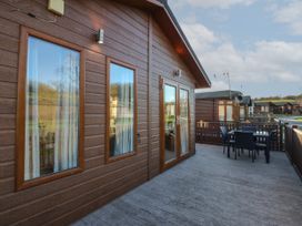 An outdoor deck area with a table and chairs attached to a wooden cabin at The Sanctuary Badgers Retreat Holiday Park near Catterick Garrison North Yorkshire