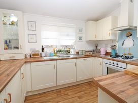 A kitchen with cabinets, sink, stove, and various appliances at The Sanctuary Badgers Retreat Holiday Park near Catterick Garrison, North Yorkshire