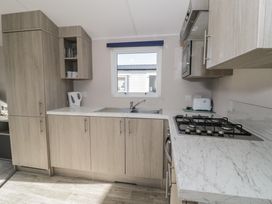 A kitchen with cabinets, sink, gas stove, and appliances at Lido Gold 120 Prestatyn