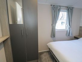 A bedroom with a wardrobe and a window at Lido Gold 120 in Prestatyn