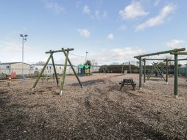 A playground with swings and a play structure at Lido Gold 120 Prestatyn