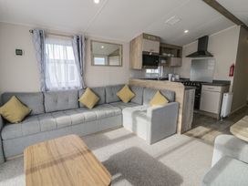 A living room with a sofa and kitchen area at Lido Gold 205 in Prestatyn