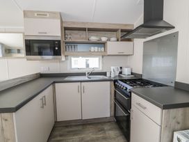 A kitchen with a gas stove and sink at Lido Gold 205 Prestatyn