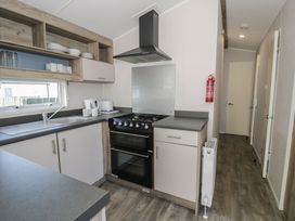 A kitchen with a sink, cooker, and cabinets at Lido Gold 273 Prestatyn