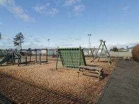 A playground with swings and climbing frame at Lido Gold 273 Prestatyn