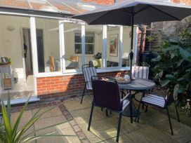 A garden with a table and chairs under an umbrella at Bay Tree Cottage, Peasenhall