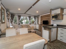 A living room with a sofa and dining area at Woodlands Gold (WO40) Ruthin